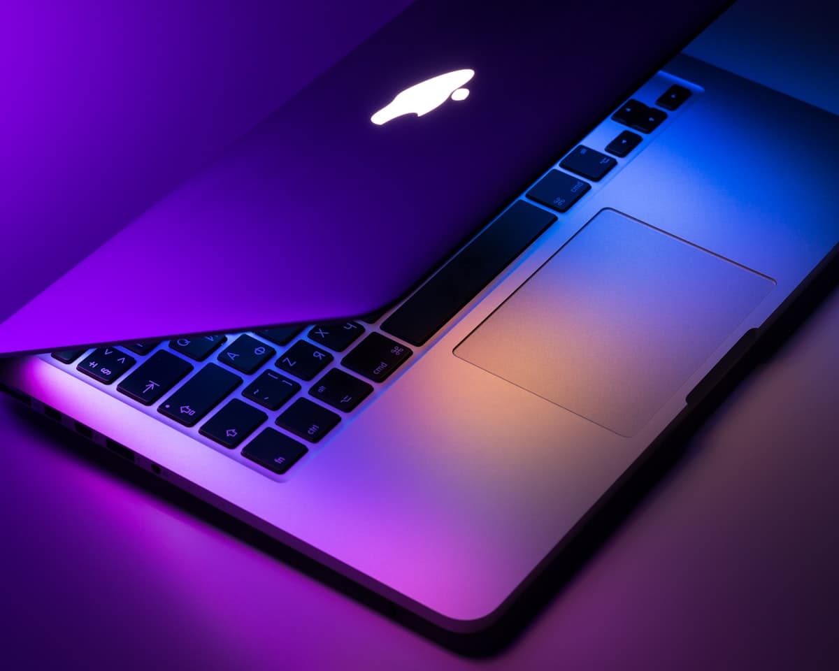 Half-open MacBook lit in purple